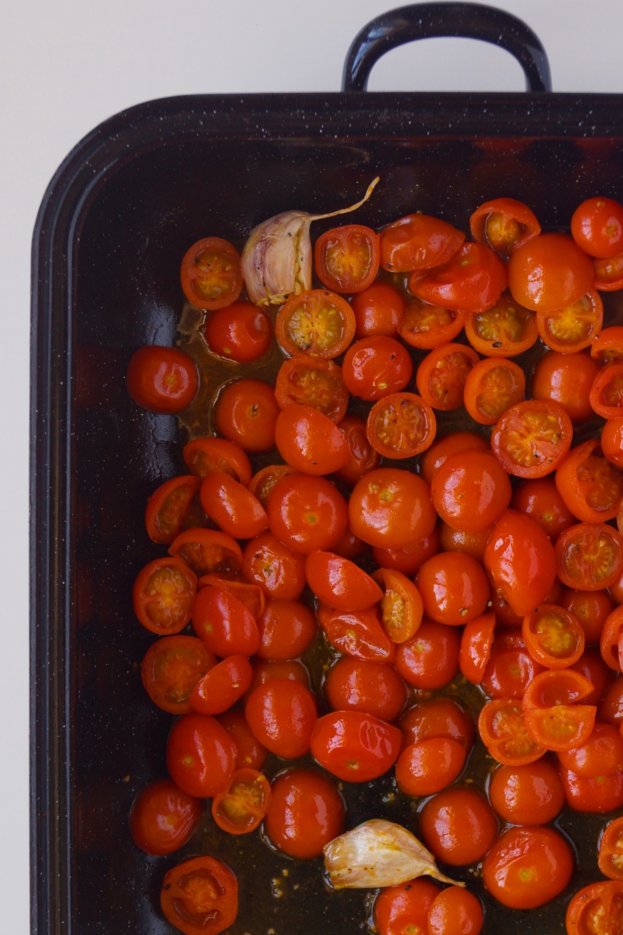 Burst, roasted tomatoes in a pan