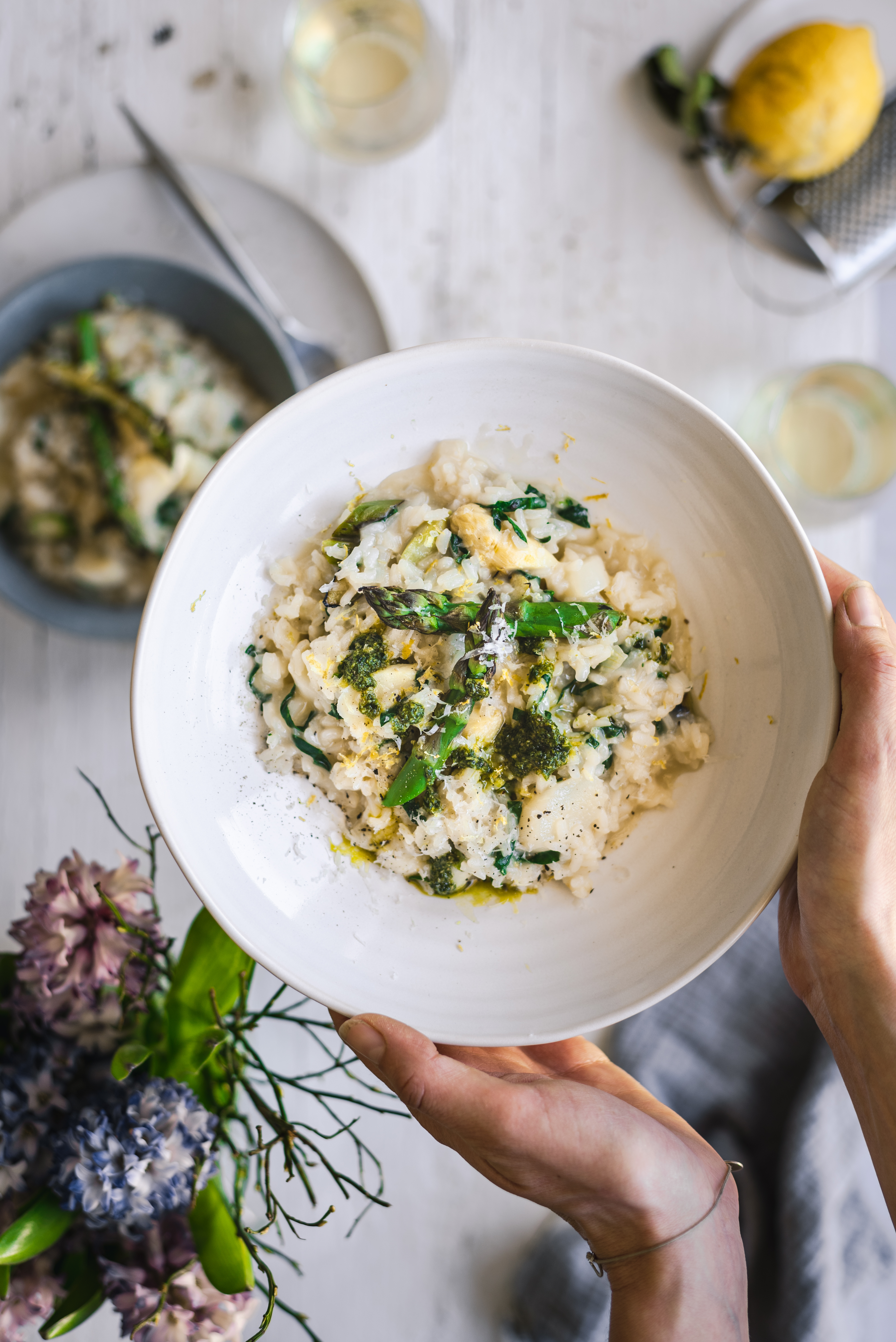 Holding a plate of creamy asparagus risotto with wild garlic pesto