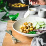 Drizzling a creamy yoghurt dressing over roasted potatoes & sliced cucumber