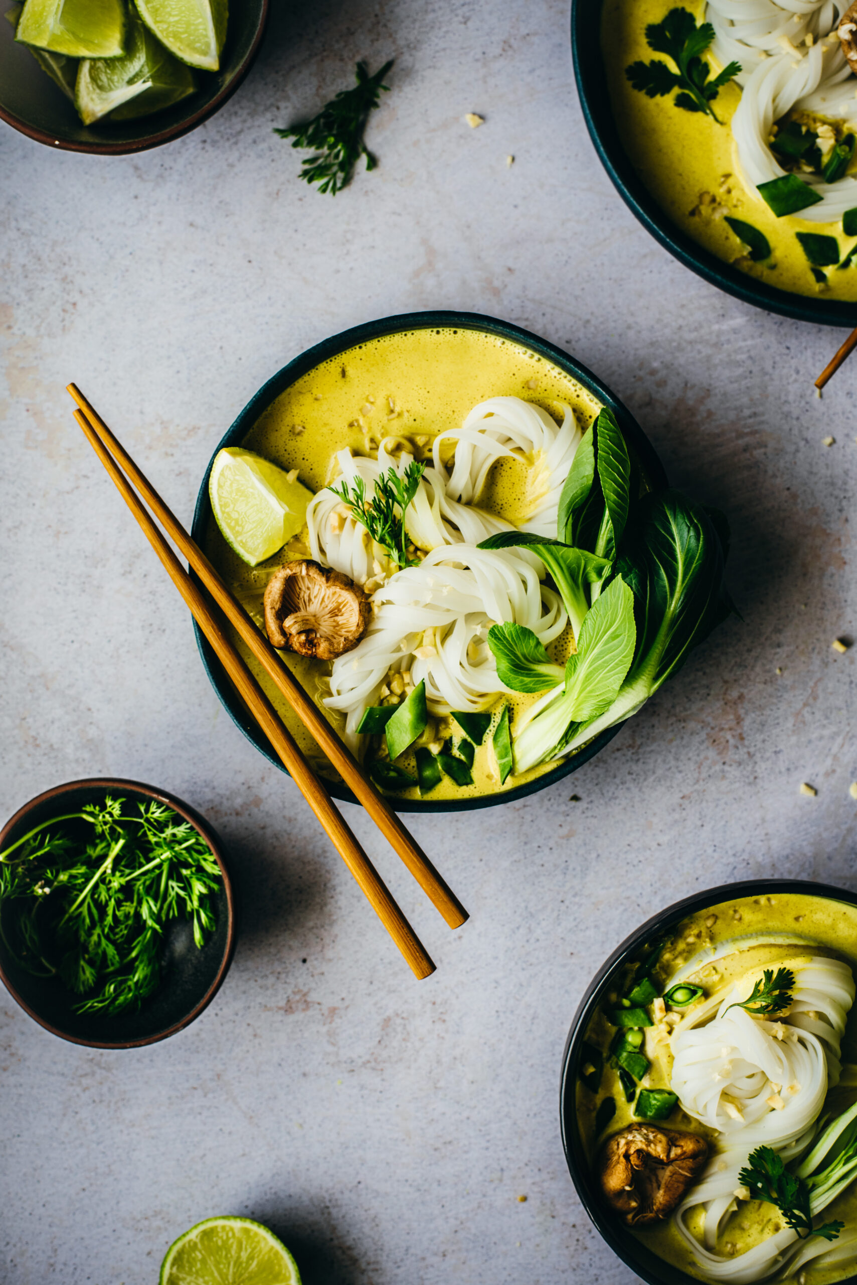 A bowl of creamy yellow curry soup with ricenoodles & green veggies