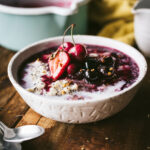 A bowl of creamy Amaranth Oat Porridge topped with freshly stewed summer berries