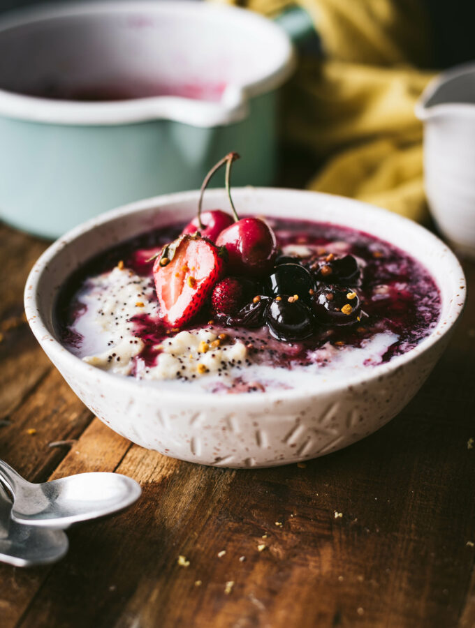 A bowl of creamy Amaranth Oat Porridge topped with freshly stewed summer berries