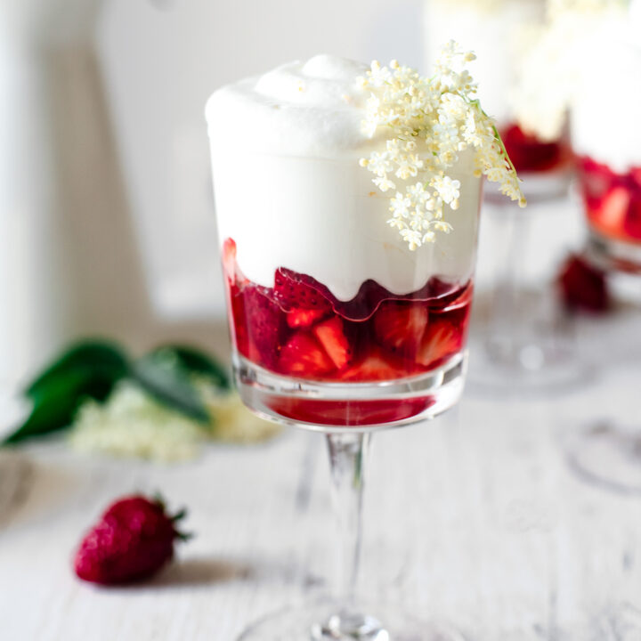 A glas jar filled with bright red strawberries & delicious white curd cream.