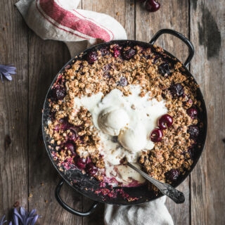 A baking dish with juicy, warm cherries topped with a crispy oat crumble