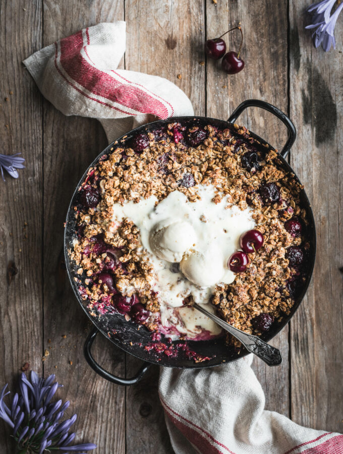 A baking dish with juicy, warm cherries topped with a crispy oat crumble