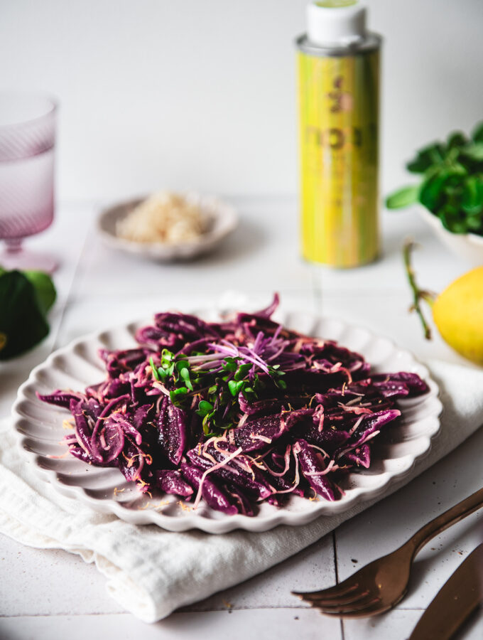 A plate of purple beetroot scissor pasta topped with horseradish and NOAN lemon oil